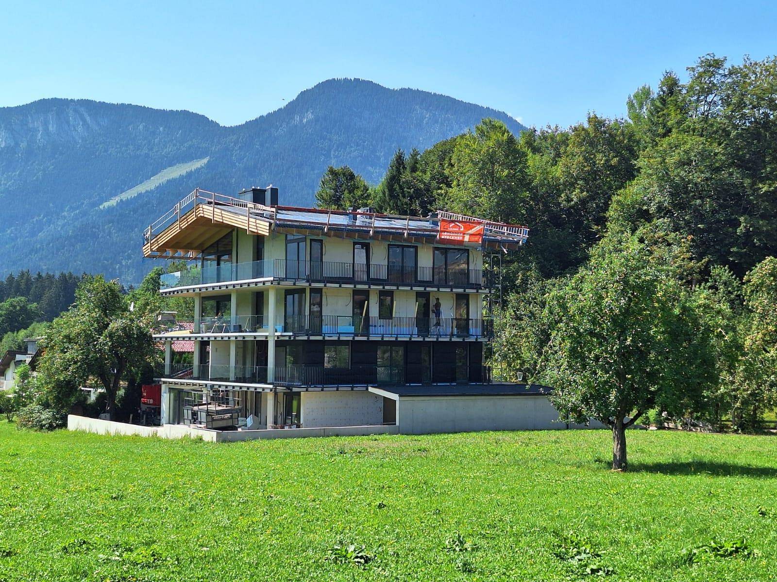 Neubau eines modernen Wohnhauses mit mehreren Balkonen und Blick auf die umliegende Berglandschaft.