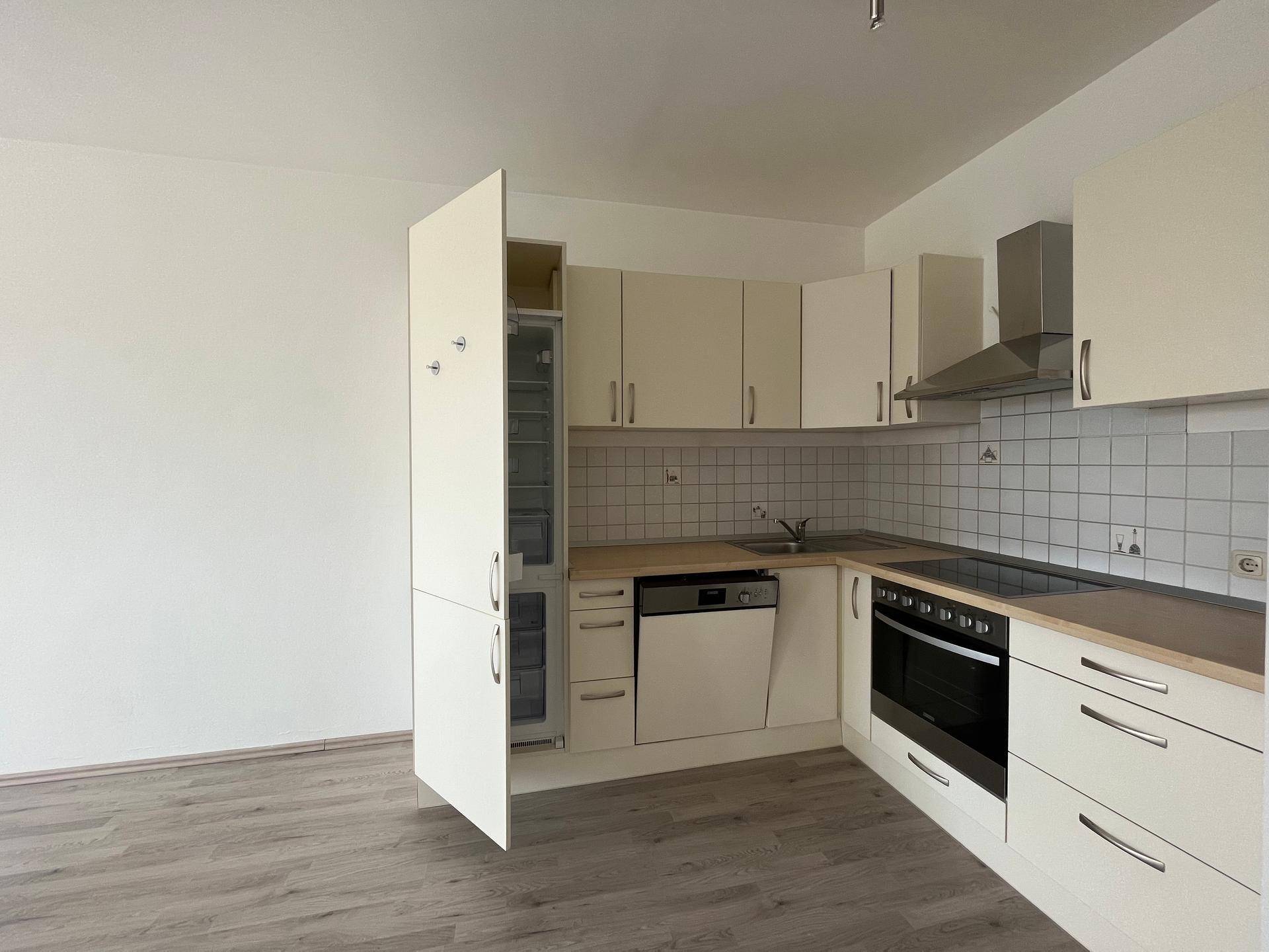 Voll ausgestattete Einbauküche mit hellen Fronten, integriertem Kühlschrank und Kochfeld.