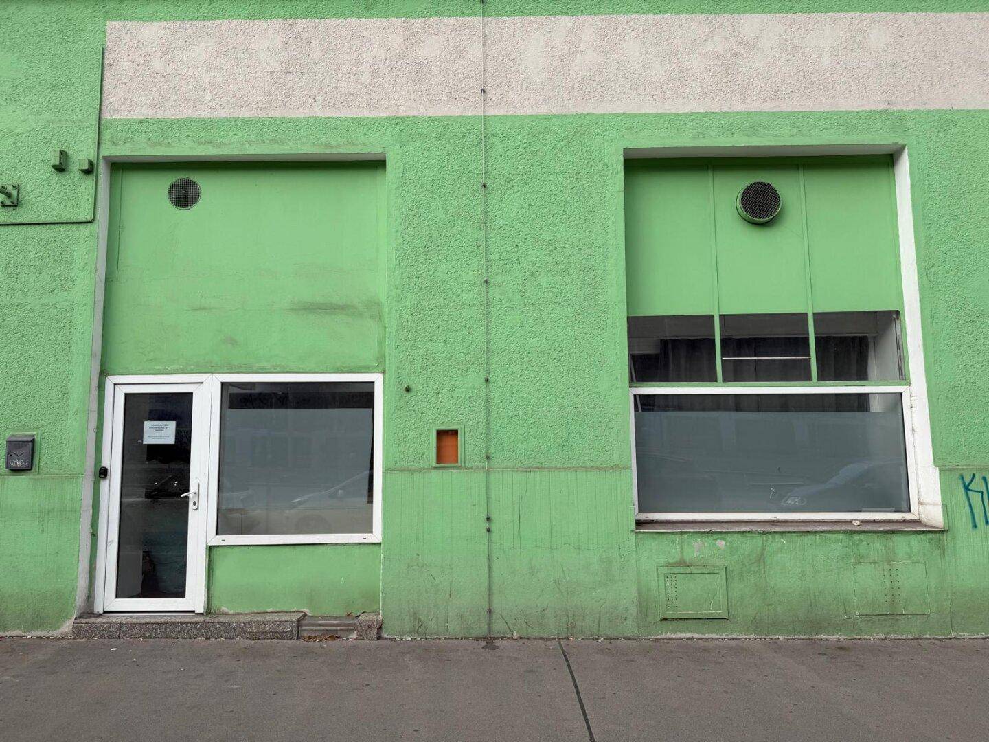 Auffällige grüne Gebäudefassade mit großen Fenstern und einem Eingangsbereich, charakteristisch für ein Gewerbegebäude.