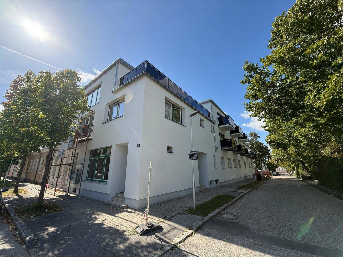 Neubau-Eckgebäude mit moderner Architektur und Balkonen, gelegen an einer ruhigen Wohnstraße.