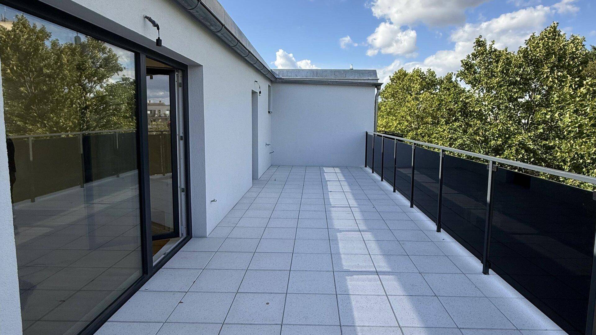 Geräumige, unmöblierte Dachterrasse mit Fliesenboden und Glasgeländer, bereit zur individuellen Gestaltung.