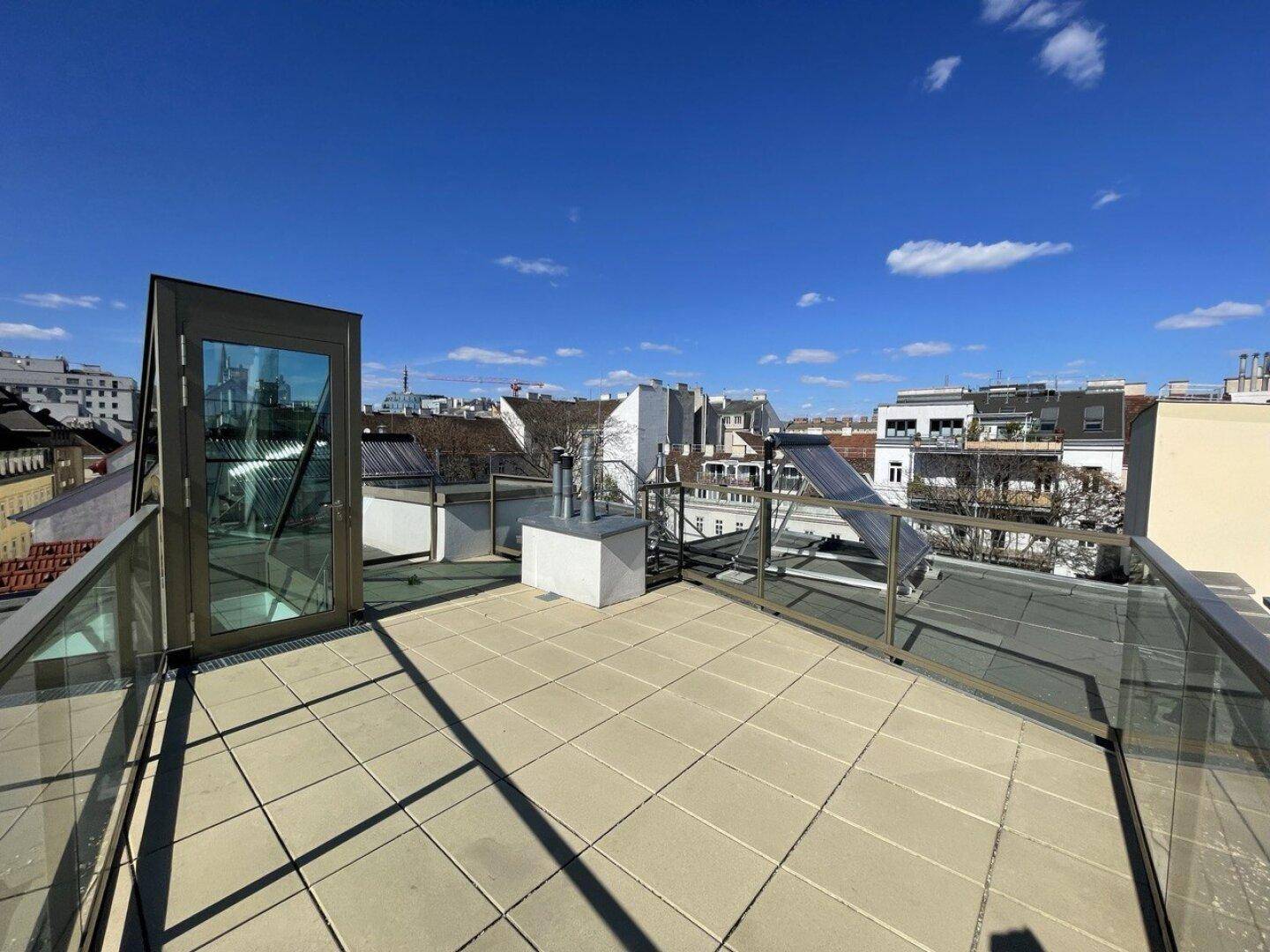 Weitläufige Dachterrasse mit Fliesenboden und Panoramablick über die umliegenden Dächer.