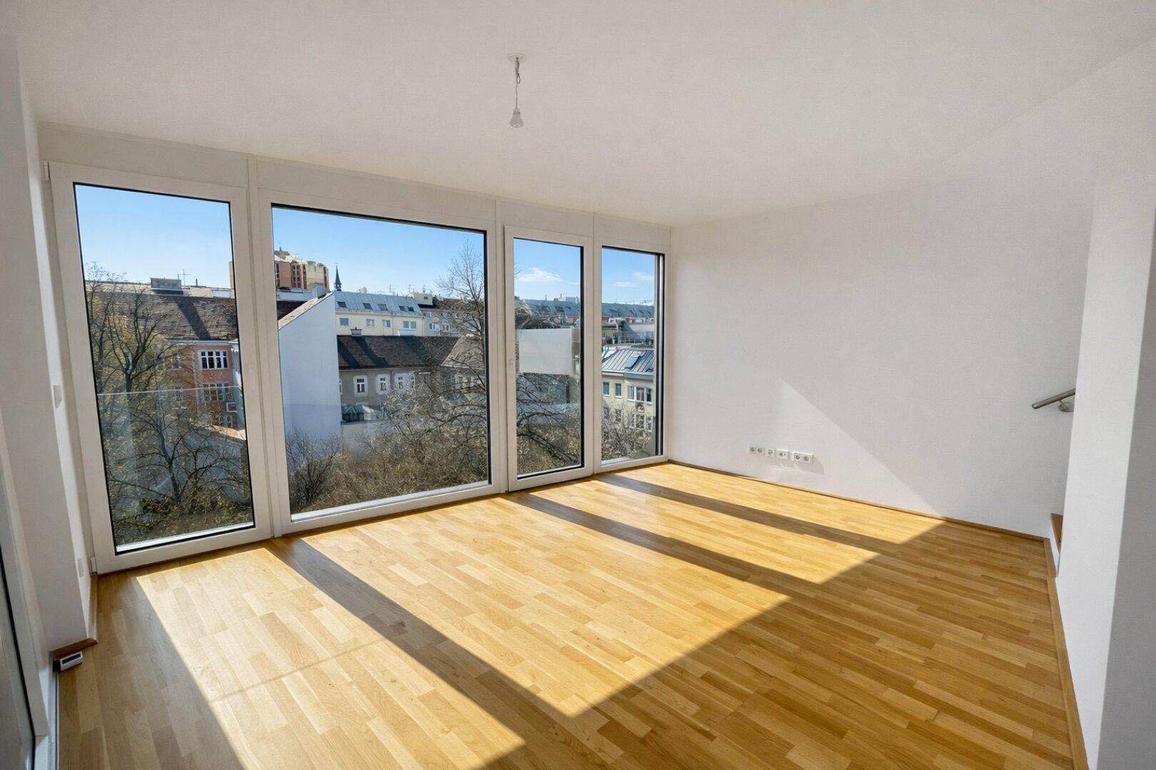 Heller Wohnraum mit Parkettboden und weitem Blick über die Stadt durch große Fenster.