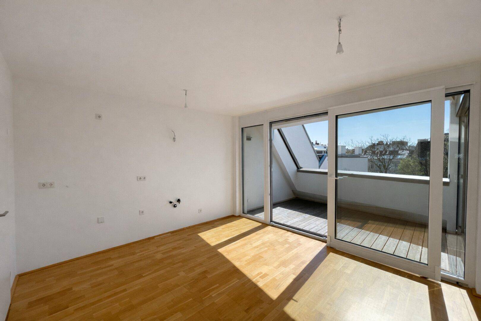 Helles Schlafzimmer mit Parkettboden, Dachschräge und direktem Zugang zum Balkon.