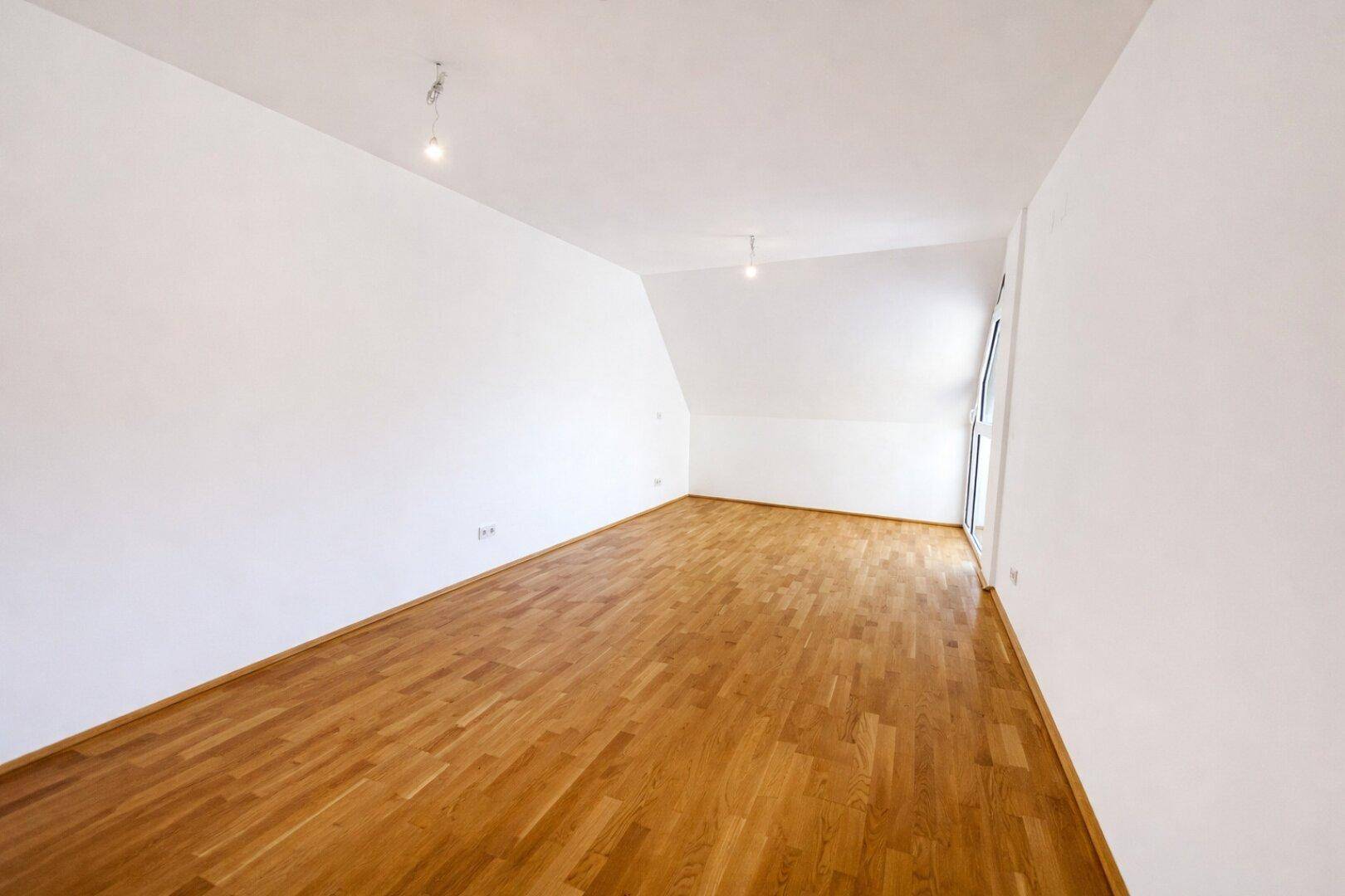 Heller Raum mit Parkettboden und Dachschräge, ideal als gemütliches Schlafzimmer oder Arbeitszimmer.