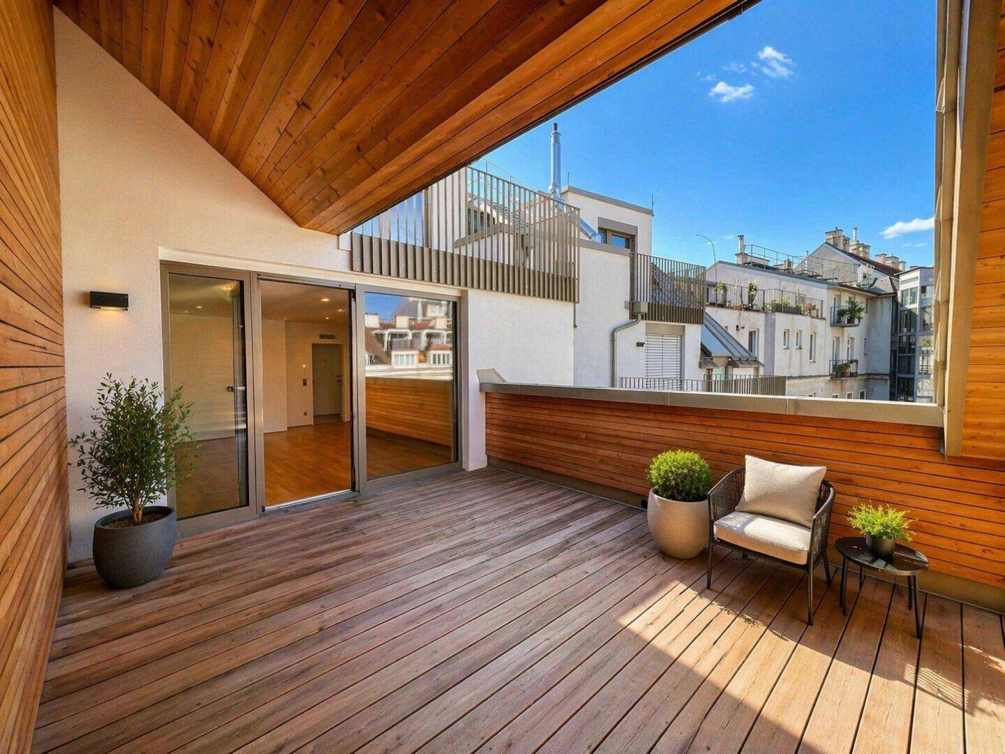 Helle Dachterrasse mit Holzboden und Zugang zu den Innenräumen, umgeben von Stadtgebäuden.
