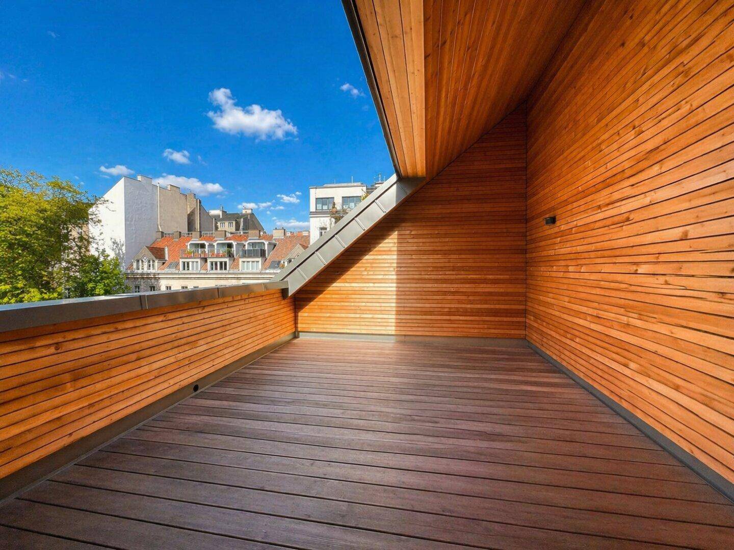 Weitläufige Dachterrasse mit Holzboden und Holzverkleidung, bietet einen weiten Blick über die Dächer.