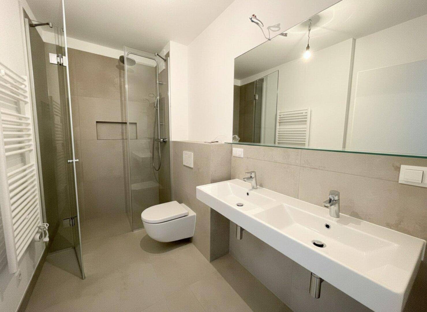 Modernes Badezimmer mit begehbarer Dusche, Doppelwaschbecken und eleganten grauen Fliesen.