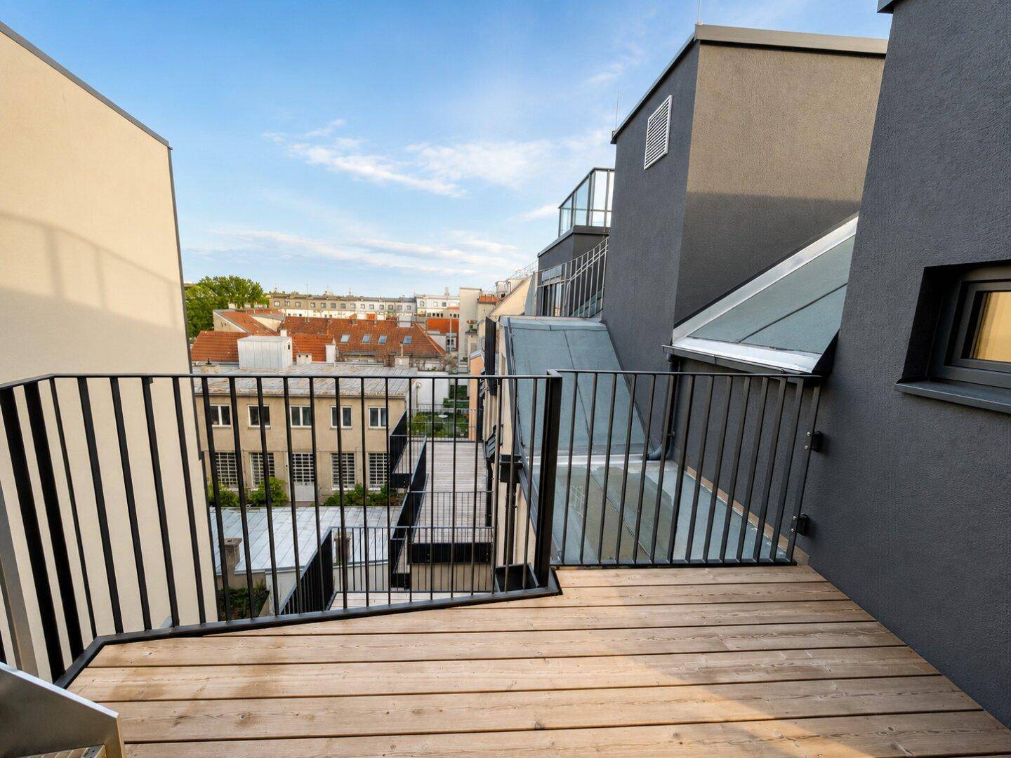 Kleiner Balkon mit Holzboden und Metallgeländer, bietet einen privaten Außenbereich.