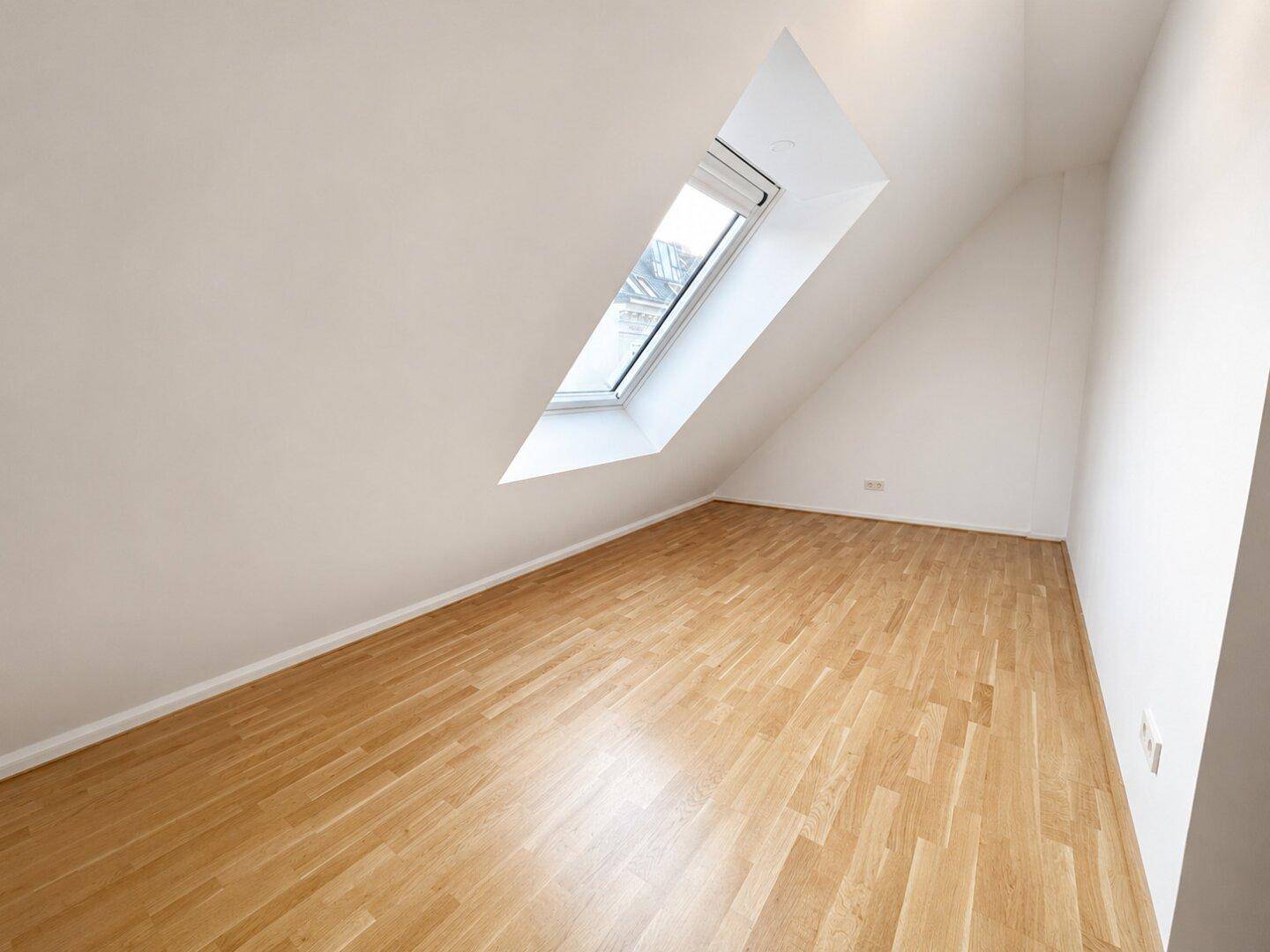 Ruhiges Schlafzimmer im Dachgeschoss mit Holzboden und einem schrägen Dachfenster.