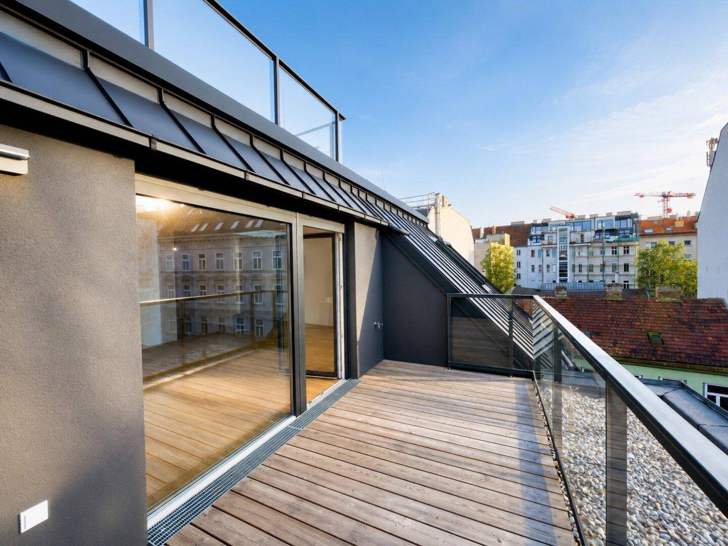 Leere Terrasse mit Holzboden und Glasgeländer, bietet einen ruhigen Außenbereich.