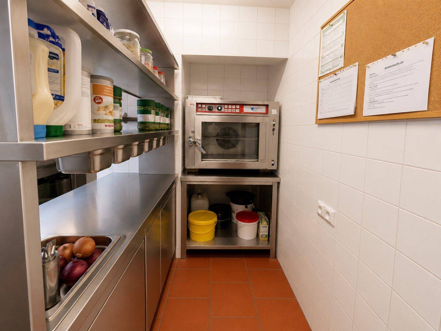 Bereich einer Gewerbeküche mit Konvektionsofen, Edelstahlregalen und weißen Fliesenwänden, für professionelles Kochen.
