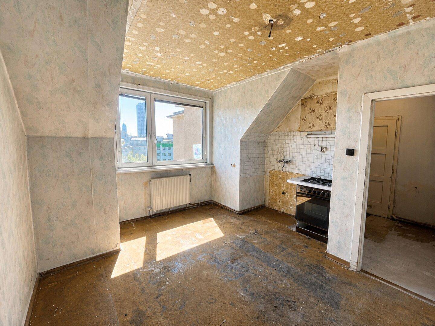 Alte Küche mit Gasherd, Fliesenrückwand und Fensterblick auf die Stadt, benötigt eine vollständige Sanierung.