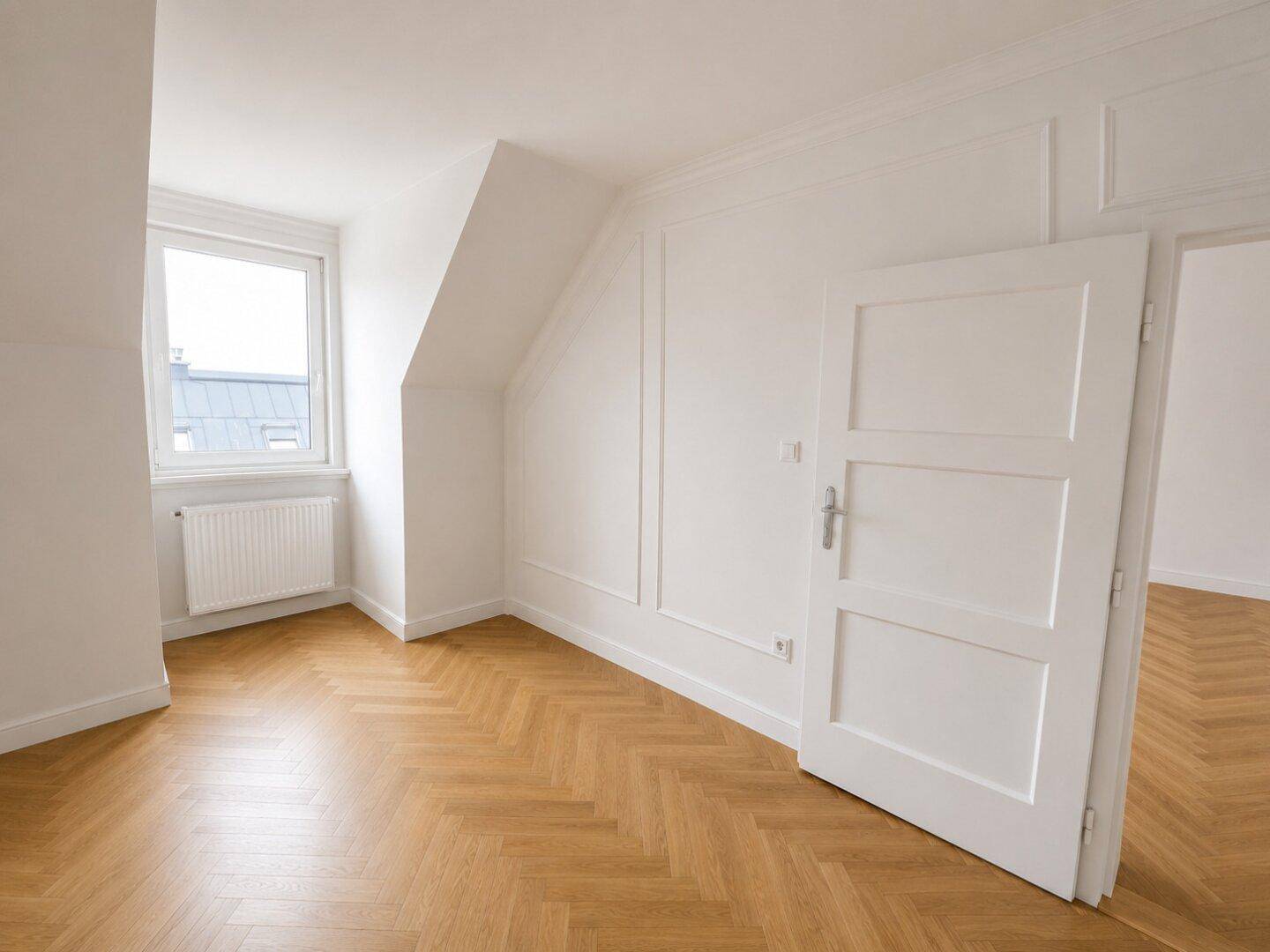 Helles, renoviertes Zimmer mit Fischgrätparkett, weißen Wänden und Fenster, ideal als Schlaf- oder Arbeitszimmer.