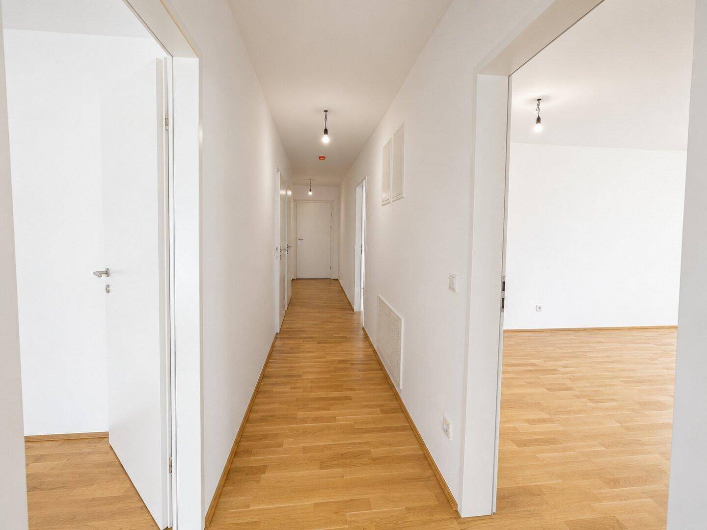Langer, heller Flur mit Holzboden und mehreren Türen zu den angrenzenden Räumen.