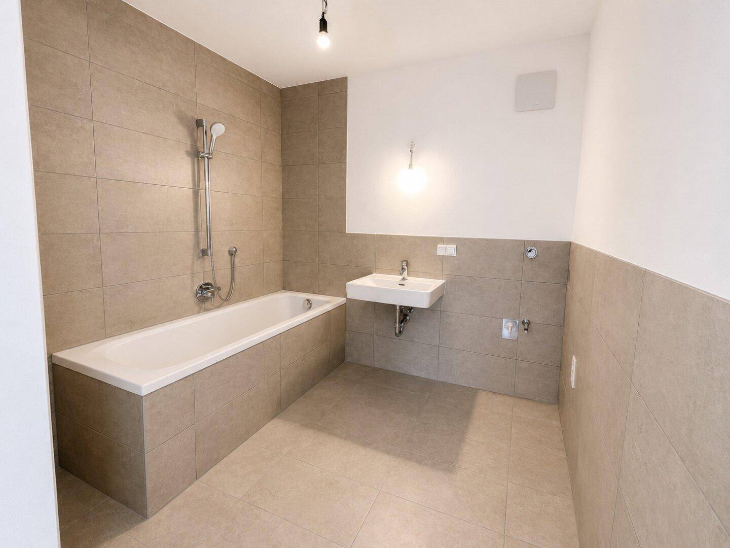 Modernes Badezimmer mit Badewanne, Waschbecken und beigefarbenen Fliesen.