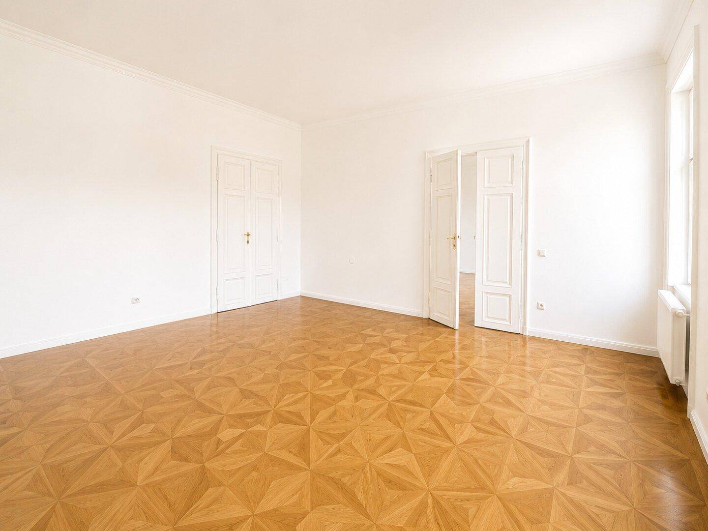 Geräumiges, helles Zimmer mit Parkettboden und Doppeltüren, ideal für flexible Nutzung.