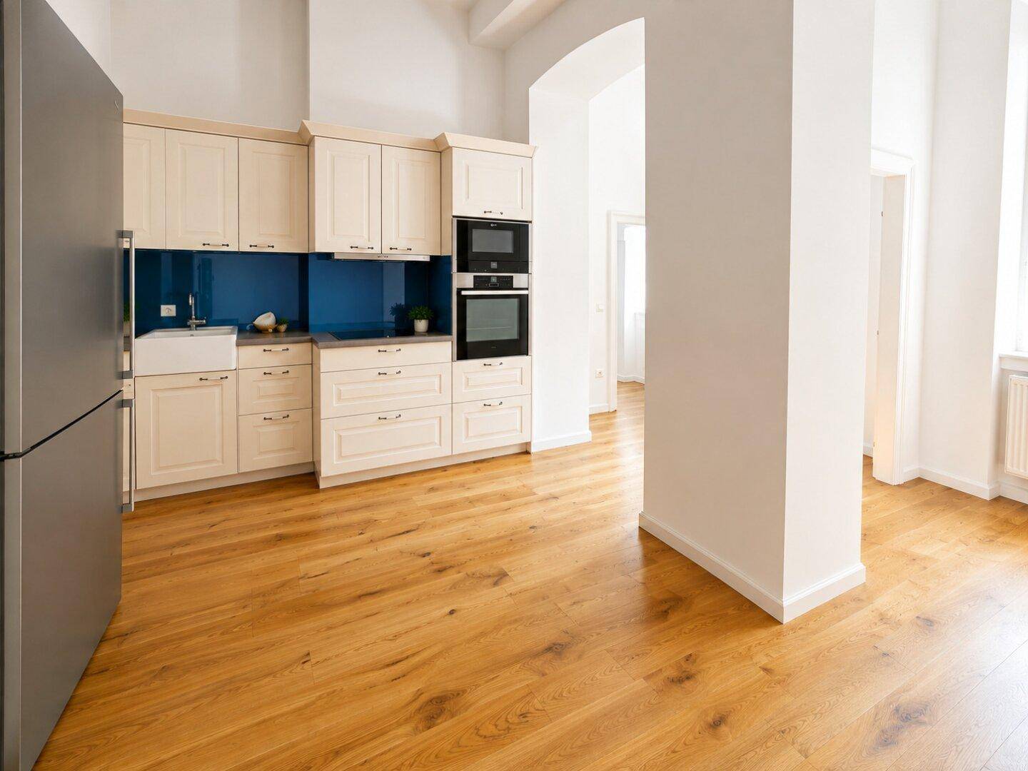 Moderne Einbauküche in hellem Design mit integrierten Geräten und Holzboden in offenem Bereich.