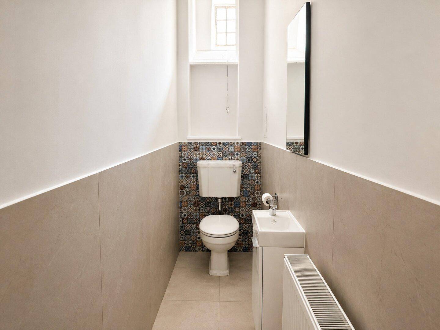 Kleines Gäste-WC mit modernem Design, Wandfliesen und Fenster für Tageslicht.