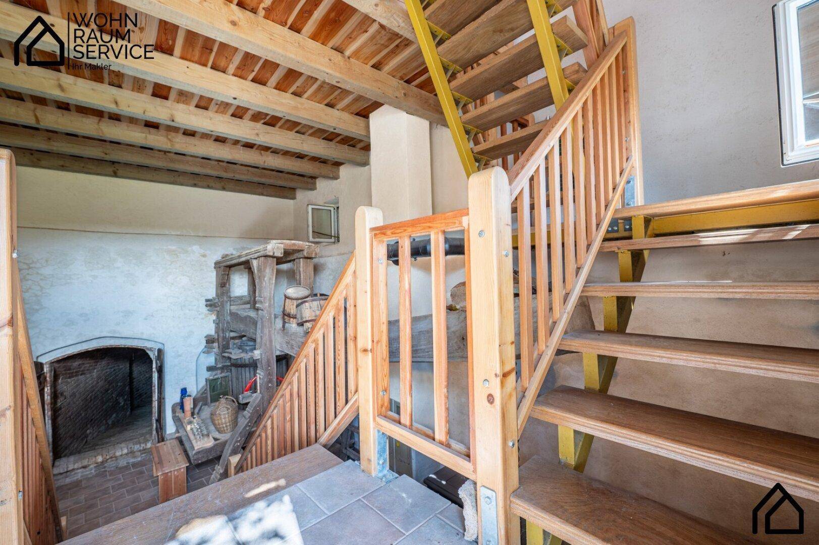 Rustikale Holztreppe mit gelben Akzenten führt zu den oberen Etagen, umgeben von Holzbalken.