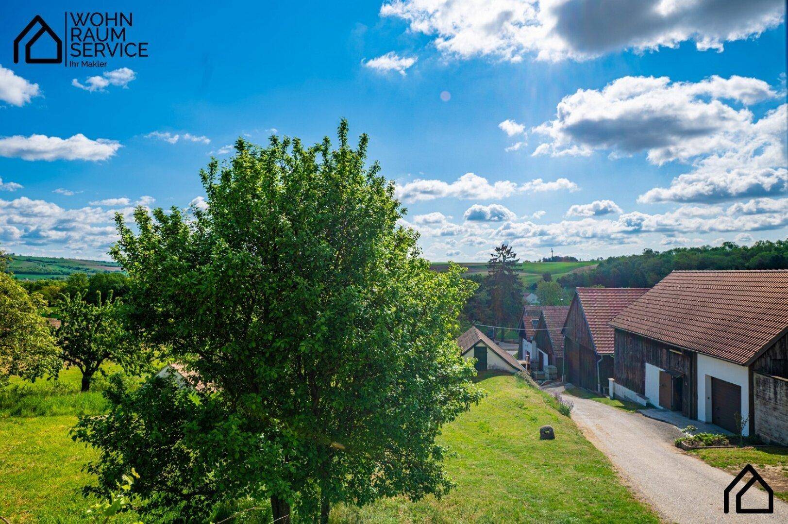 Malerischer Blick über eine ländliche Landschaft mit traditionellen Häusern und grünen Hügeln.