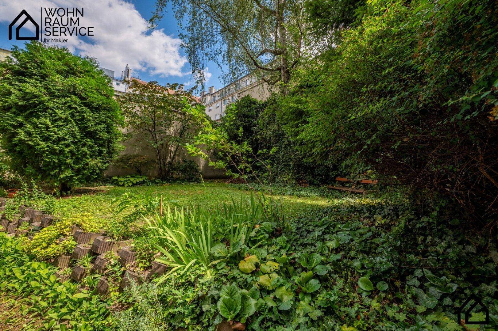Idyllischer Garten mit üppigem Grün, Rasenfläche und einer kleinen Holzbank.