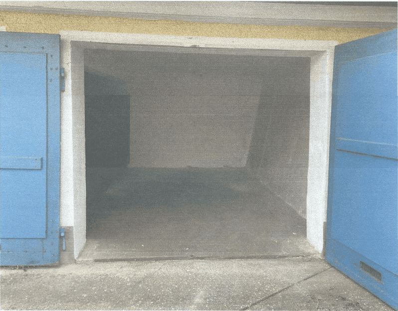Leerer Innenraum einer Garage oder eines Lagerraums mit Betonboden und blauen Flügeltüren.
