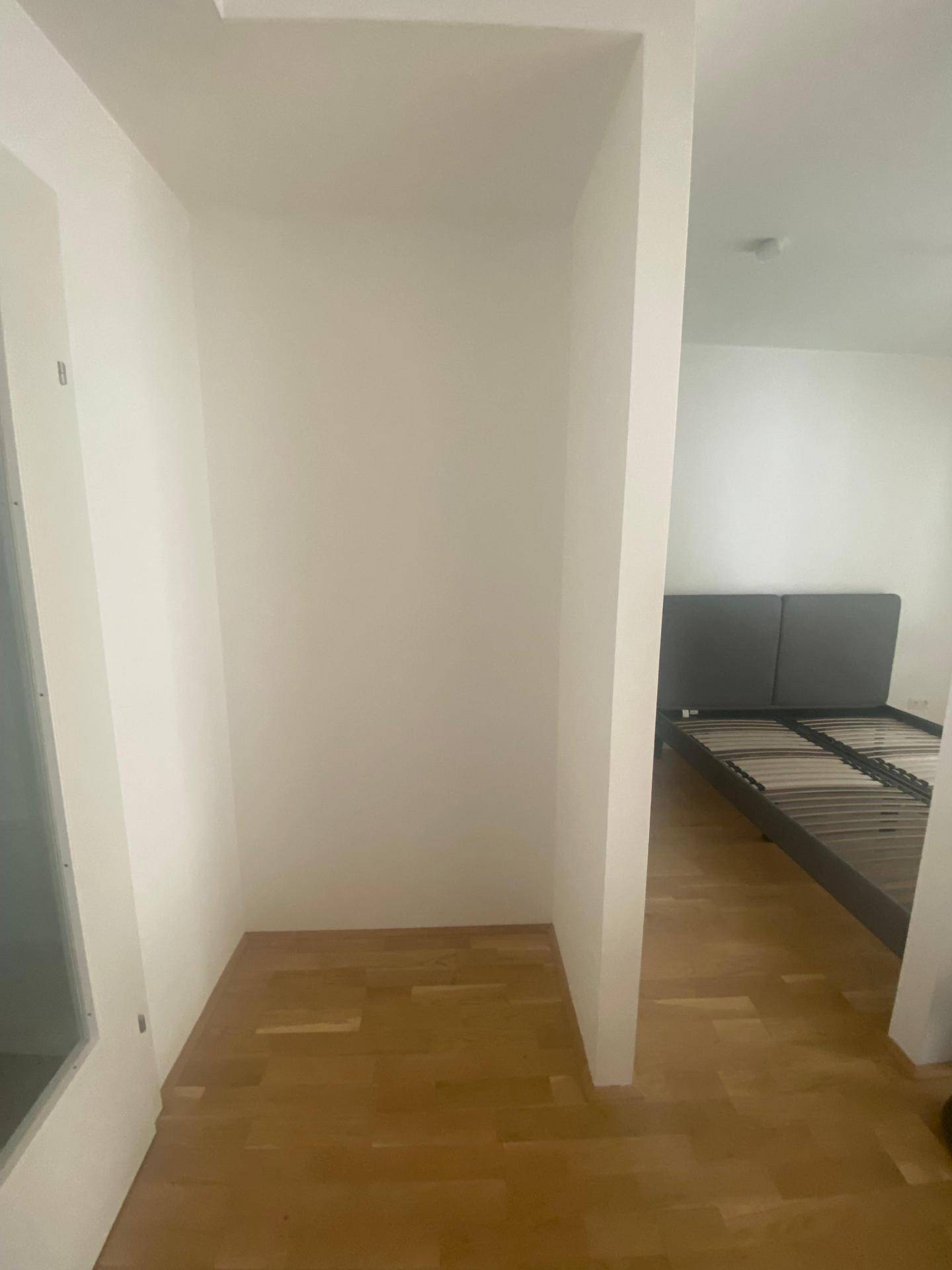 Leere Nische mit Parkettboden, ideal für einen Einbauschrank oder als Abstellfläche.