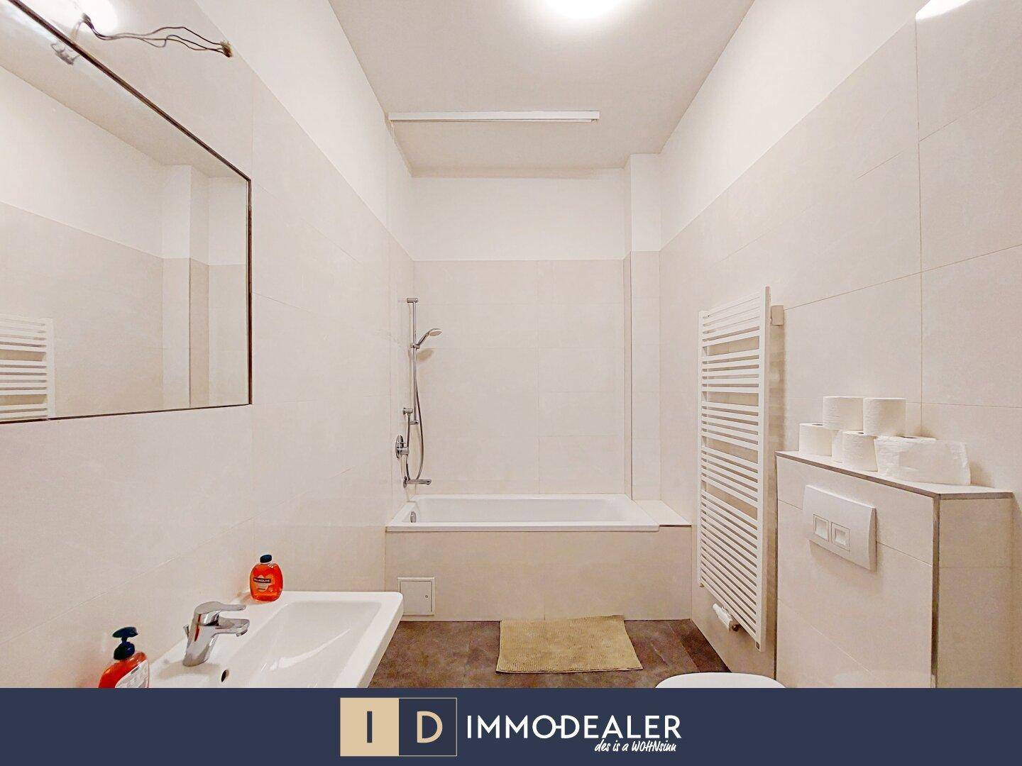 Modernes Badezimmer mit Badewanne, Waschbecken und beheiztem Handtuchhalter.