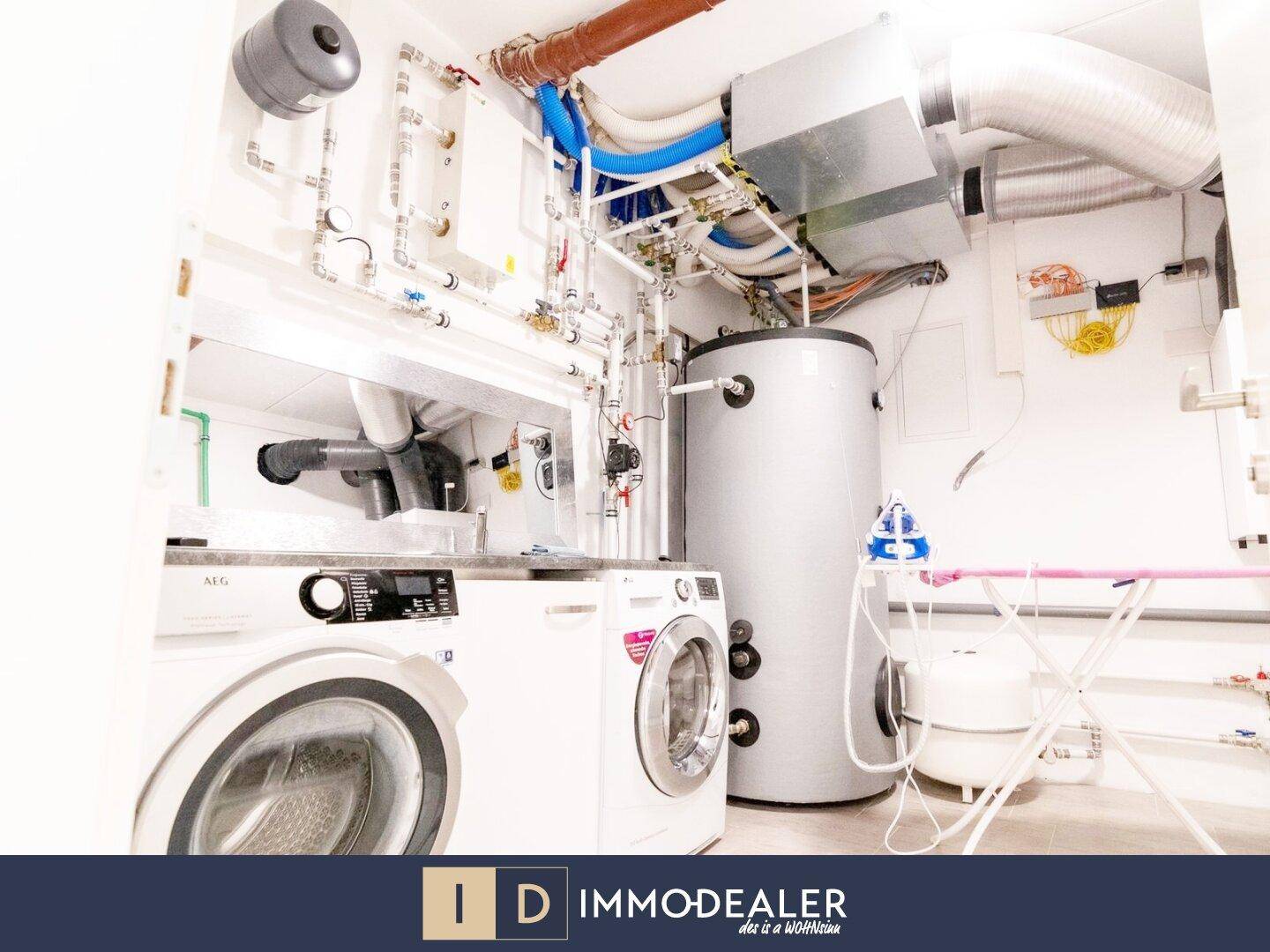 Funktionaler Hauswirtschaftsraum mit Waschmaschinen, Warmwasserspeicher und sichtbaren Installationen.