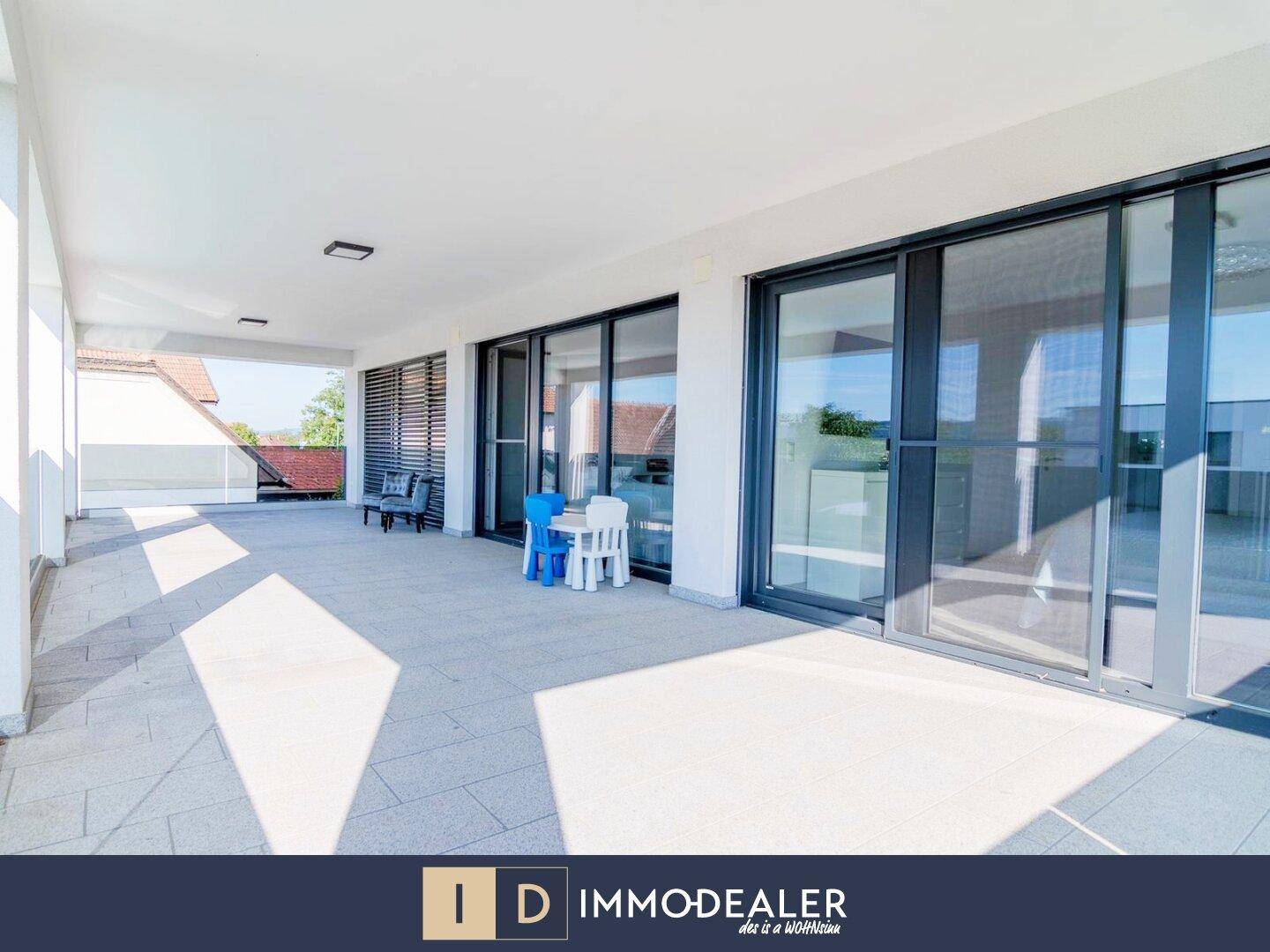 Geräumige überdachte Terrasse mit Fliesenboden und Zugang zu den Innenräumen, ideal für Entspannung.