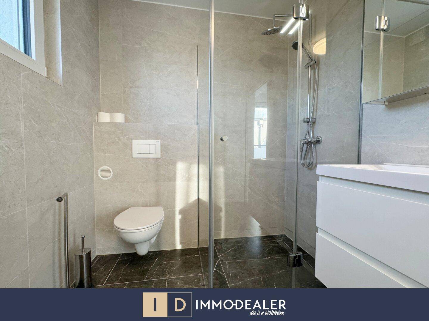 Modernes Badezimmer mit begehbarer Dusche, Wand-WC und Doppelwaschbecken, hell gefliest.