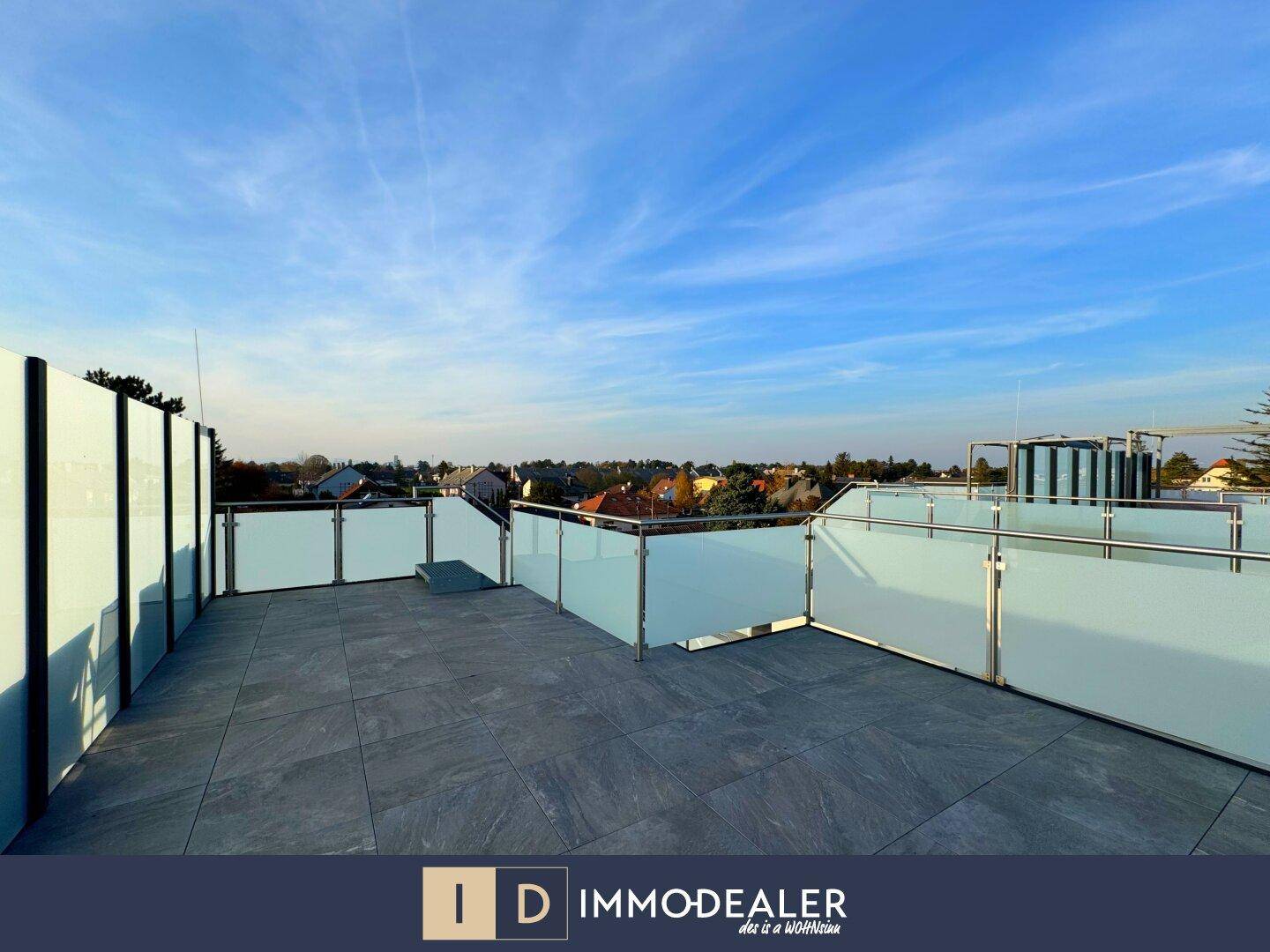 Weitläufige Dachterrasse mit Glasgeländer und weitem Blick über die Umgebung.