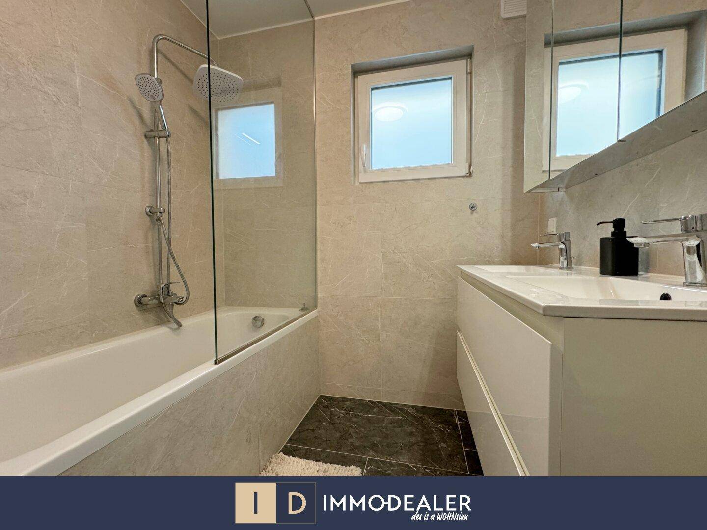 Helles Badezimmer mit Badewanne, Dusche und Doppelwaschbecken, modern gefliest.