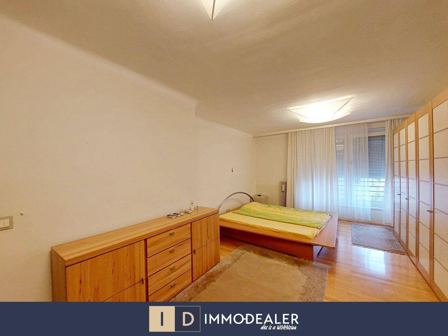 Schlafzimmer mit Holzbett, Einbauschränken und Parkettboden.