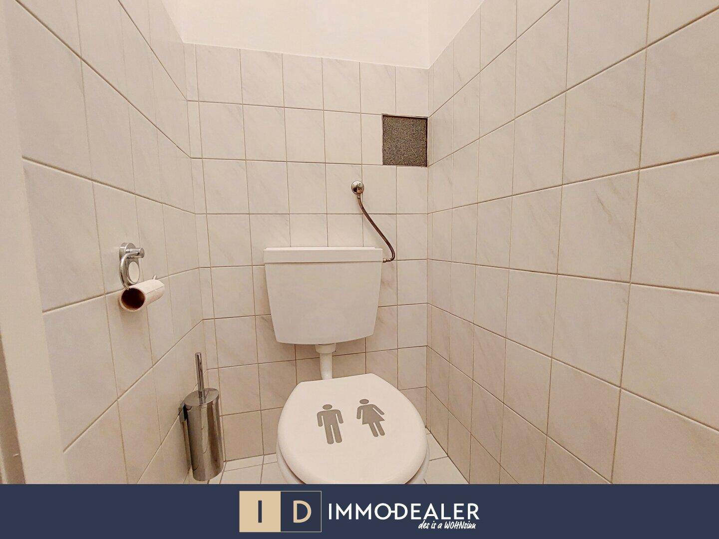Kleines WC mit weißen Wand- und Bodenfliesen und einfacher Toilette.