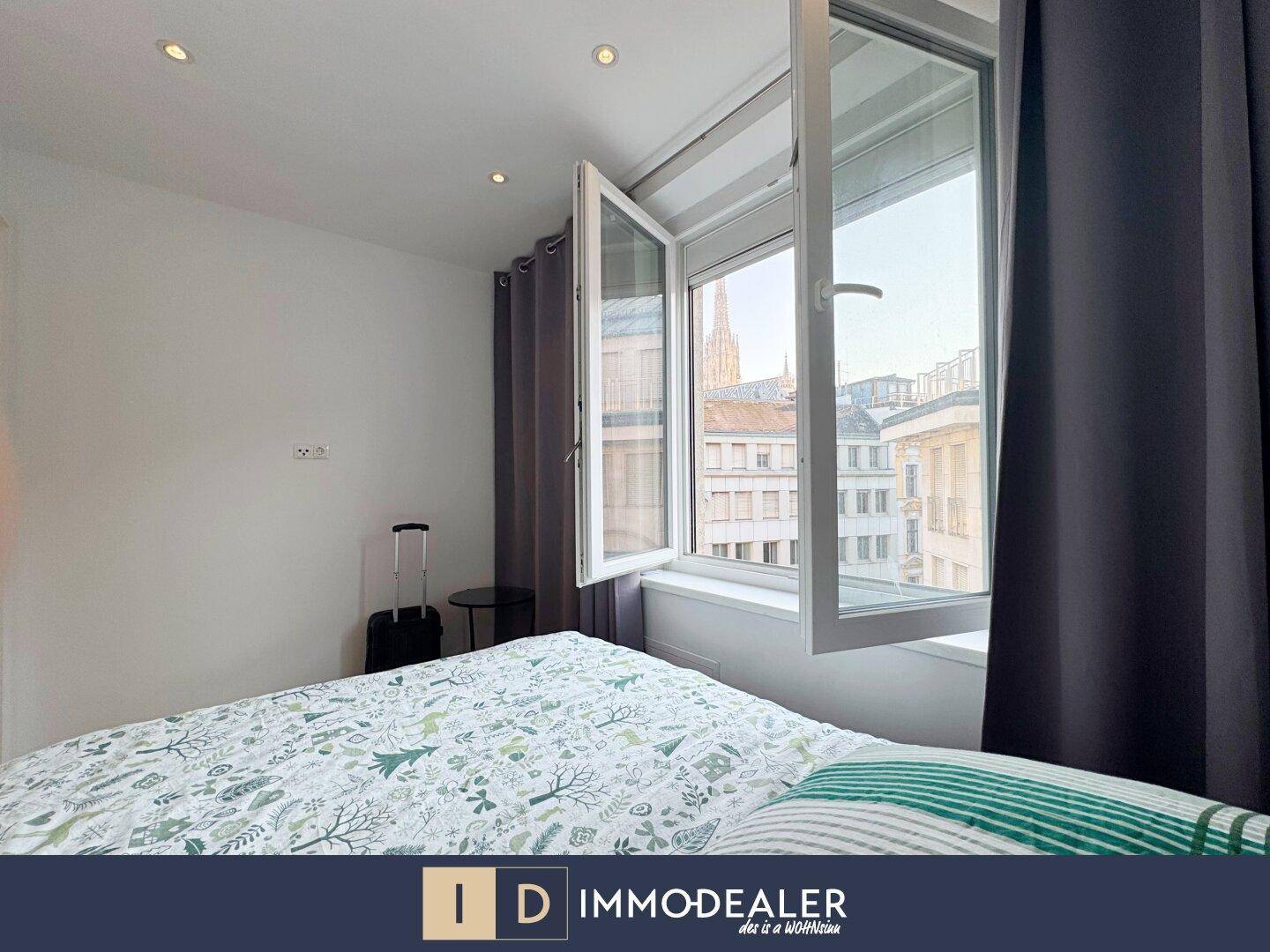 Helles Schlafzimmer mit Doppelbett und Blick aus dem Fenster auf die Stadtarchitektur.