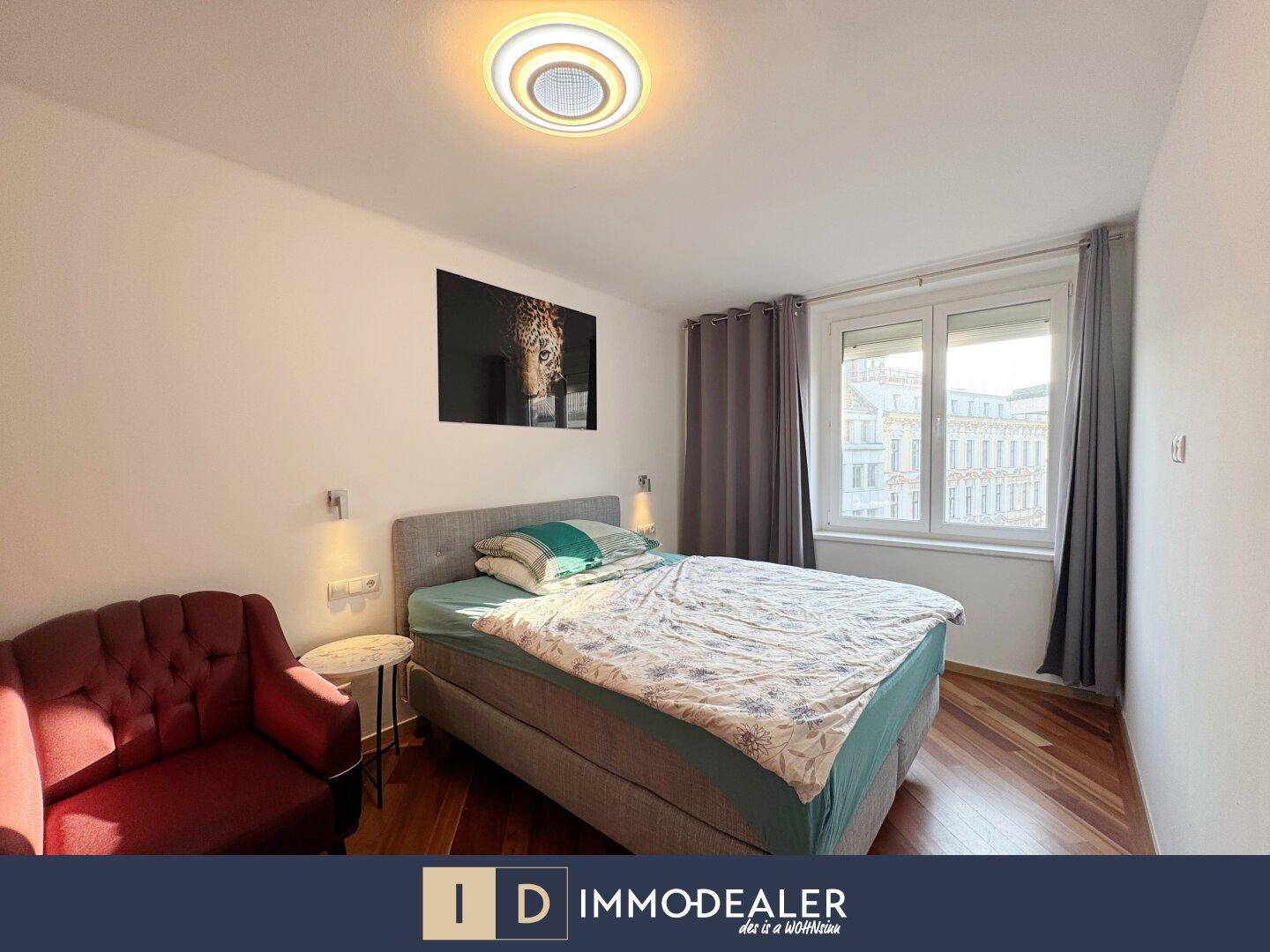 Komfortables Schlafzimmer mit Doppelbett, rotem Sessel und dunklem Holzboden.
