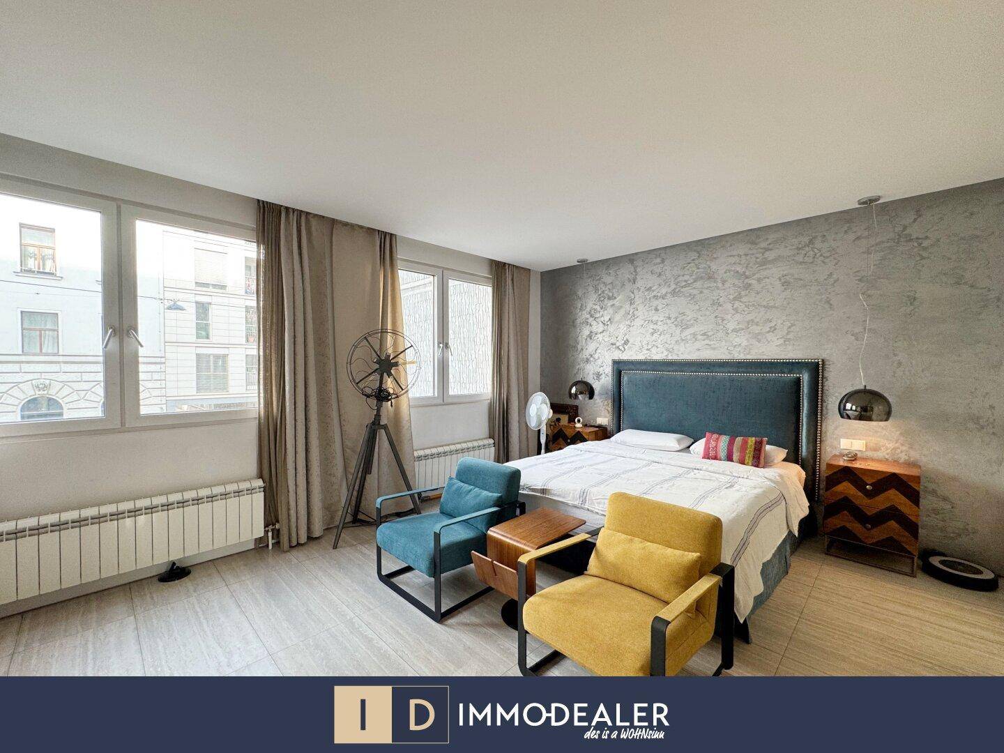 Helles Schlafzimmer mit großzügigen Fenstern, Fliesenboden und modernen Sesseln.