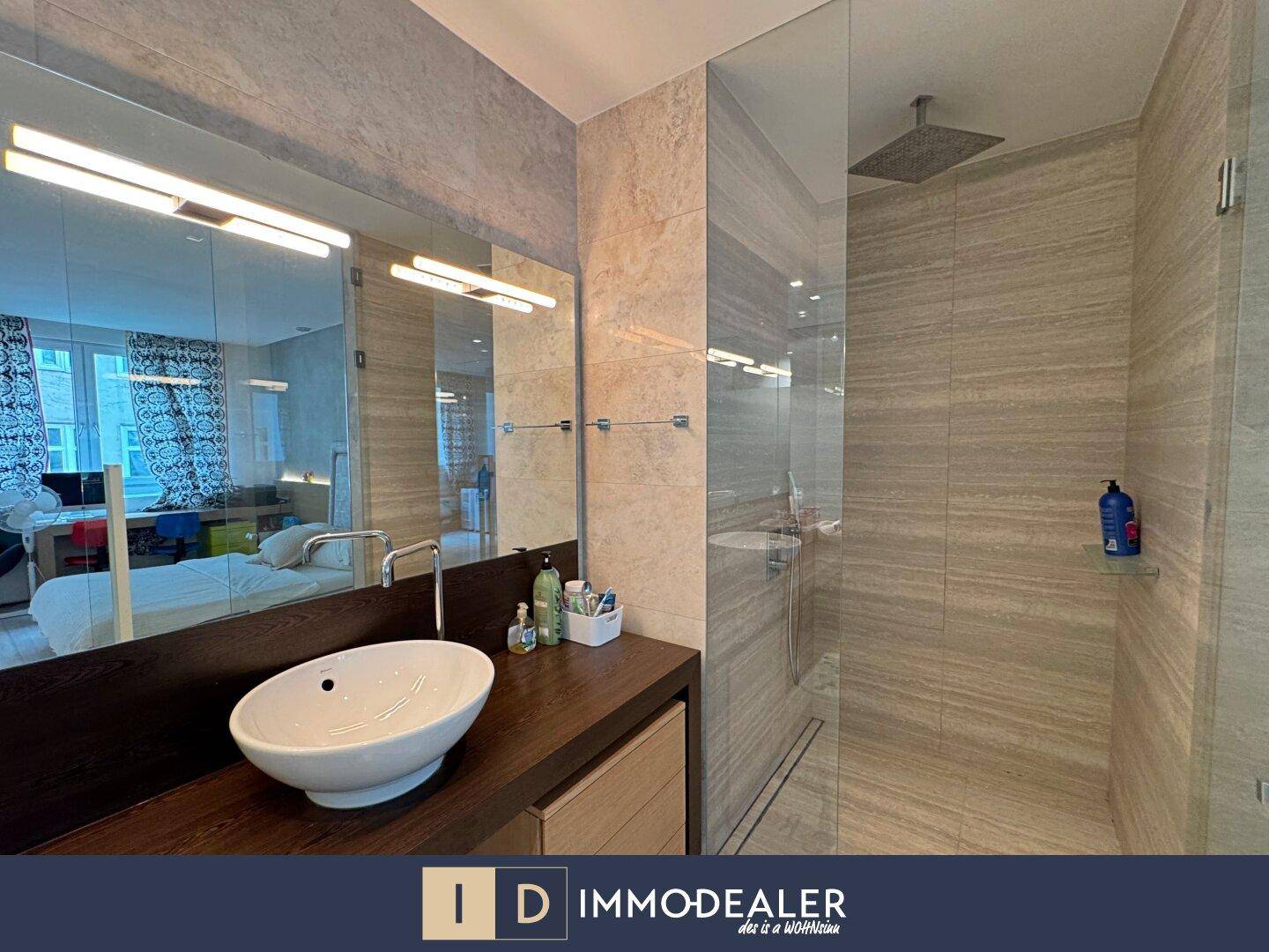 Elegante Regendusche mit Glasabtrennung und hochwertigen Fliesen im Badezimmer.