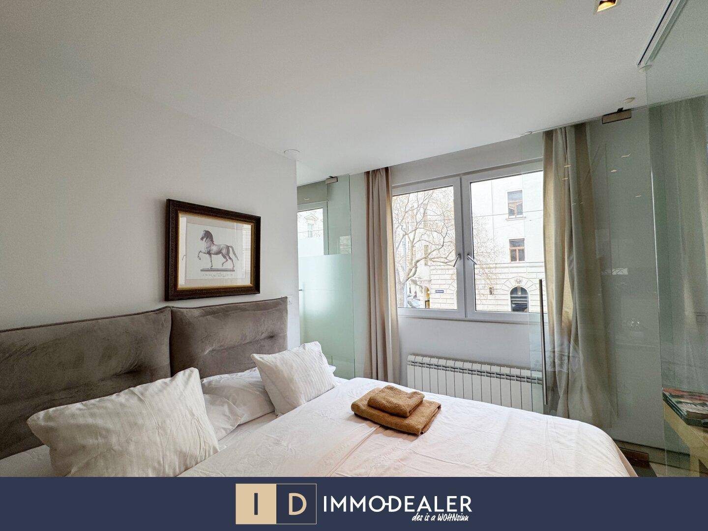Helles Schlafzimmer mit großem Fenster und Blick auf die Straße.