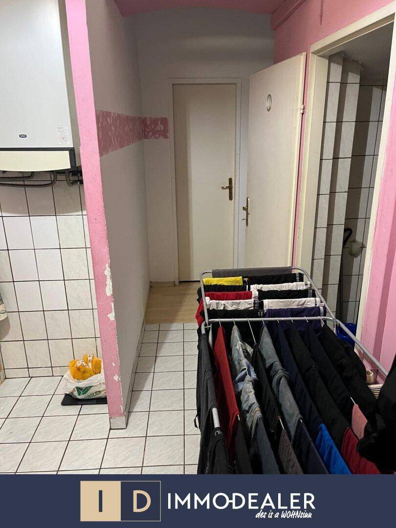 Hauswirtschaftsraum mit Wäscheständer, Warmwasserbereiter und rosa gestrichenen Wänden.