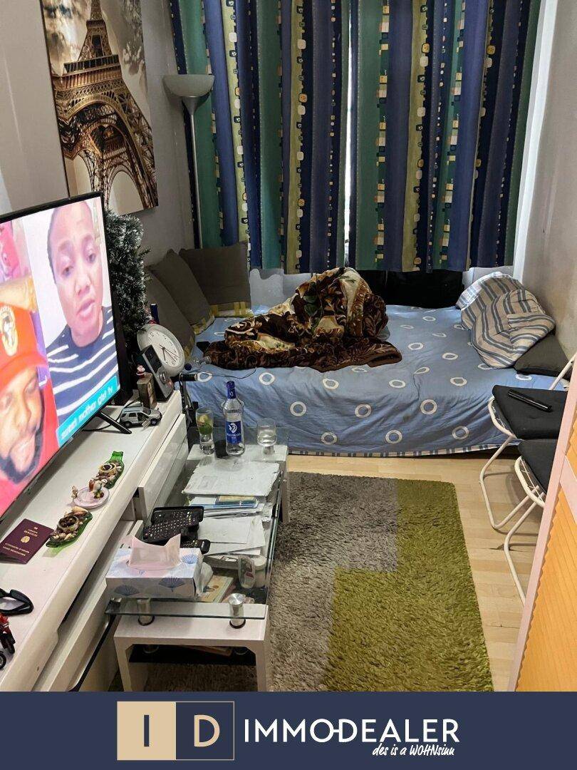 Wohnzimmer mit Schlafsofa, Fernseher und bunten Vorhängen, eingerichtet für gemütliches Beisammensein.
