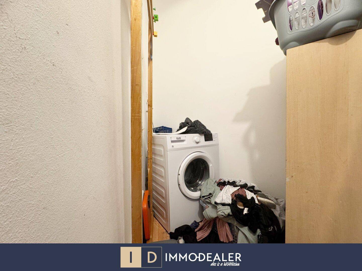 Kleiner Raum mit Waschmaschine und Wäschekorb, ideal als Hauswirtschaftsraum.
