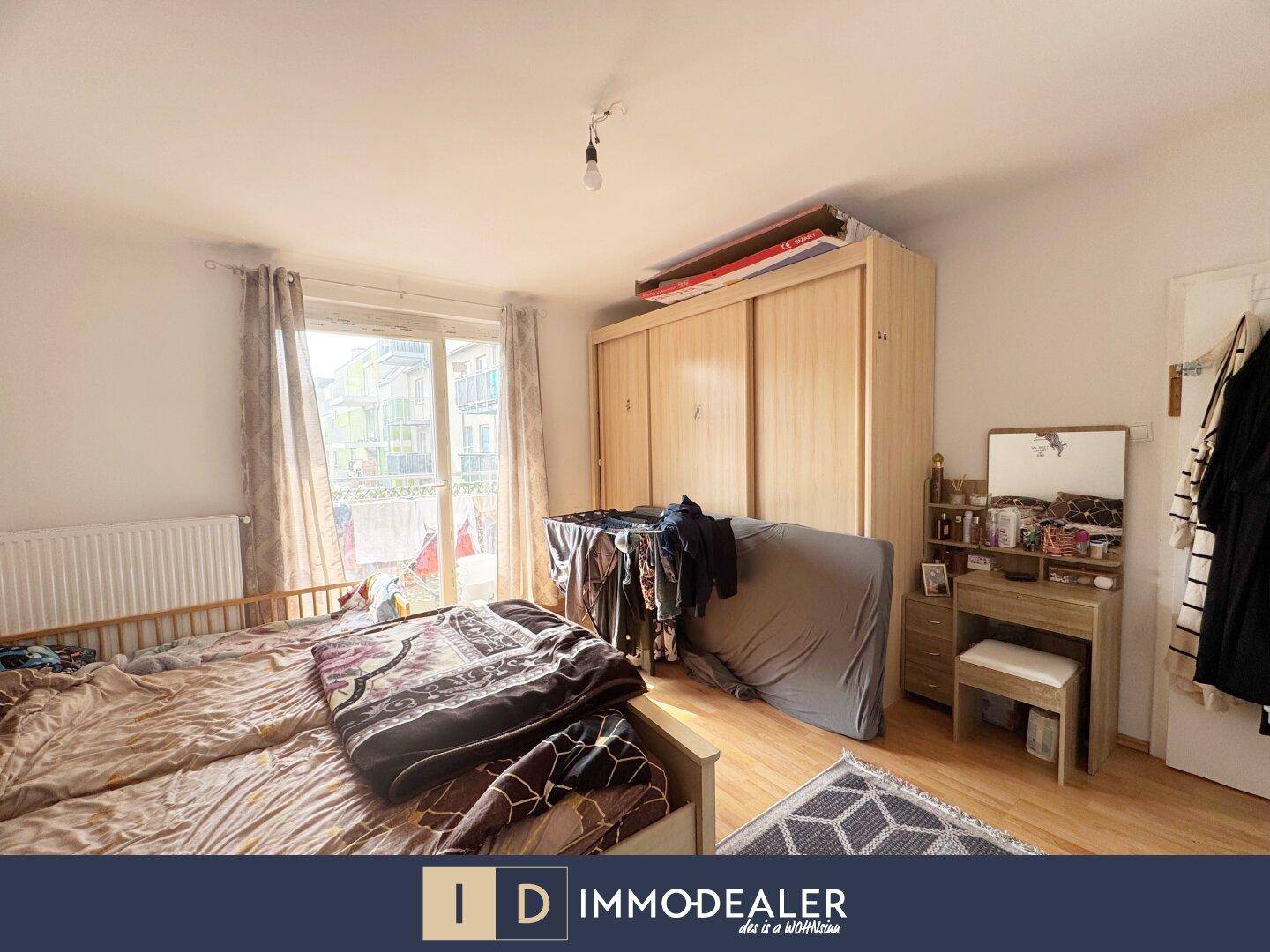 Helles Schlafzimmer mit großem Kleiderschrank, Bett und Zugang zum Balkon.