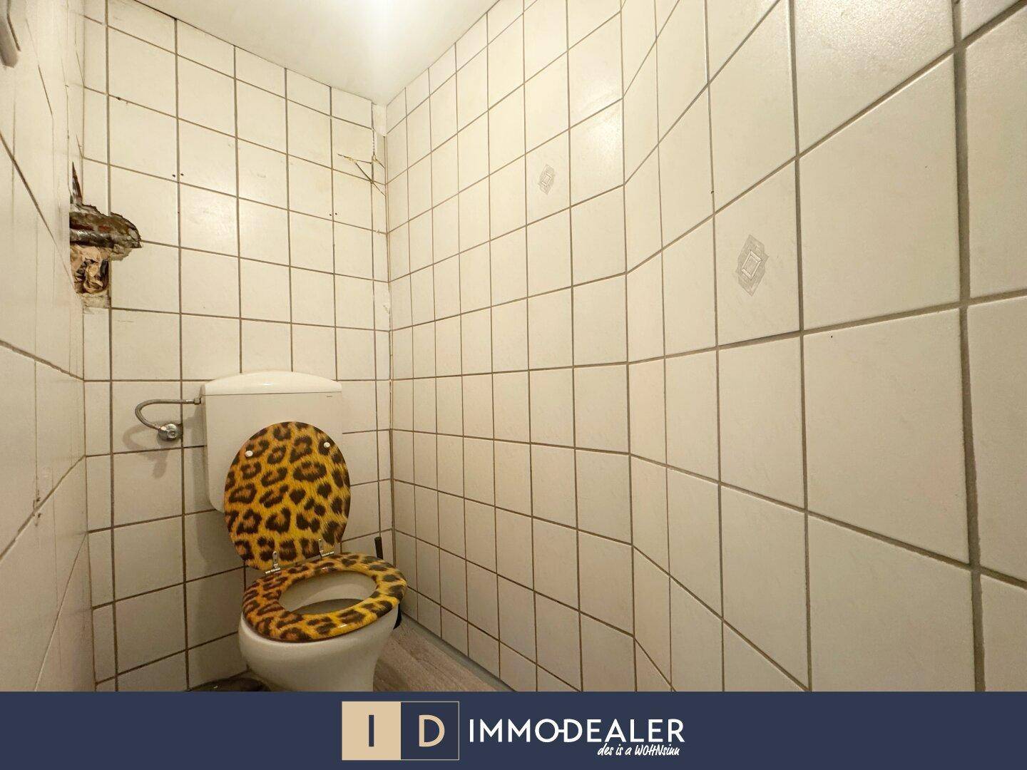 Separate Toilette mit Fliesenwänden und einem auffälligen Leopardenmuster-Sitz.