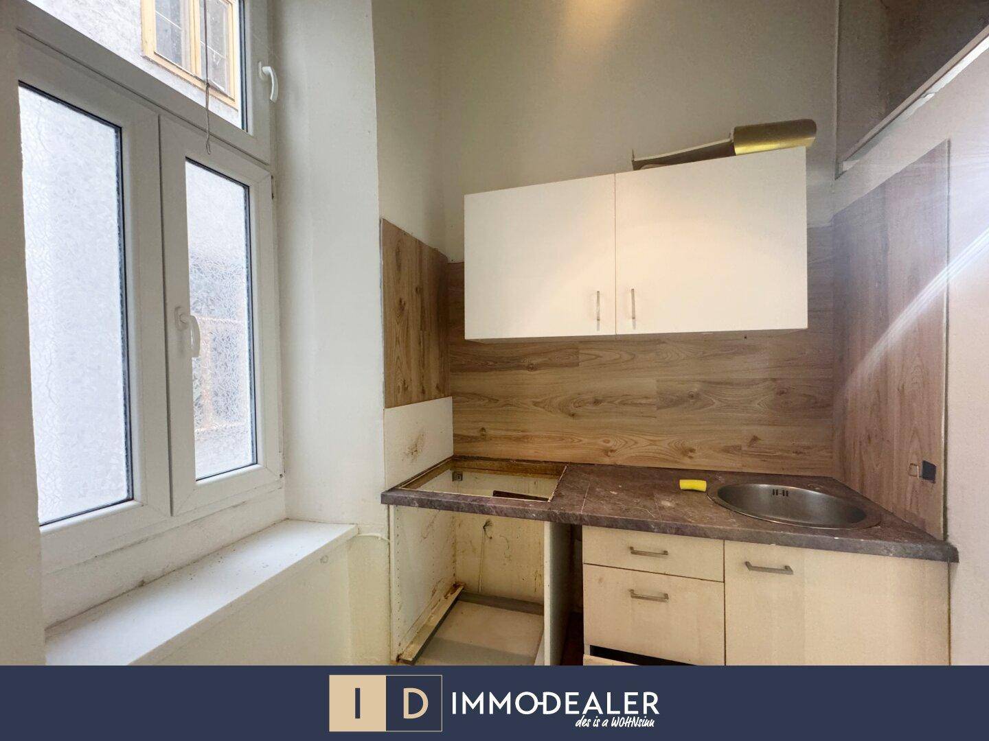 Kleine Küchenzeile mit Spüle und Oberschränken, bereit für die individuelle Ausstattung.