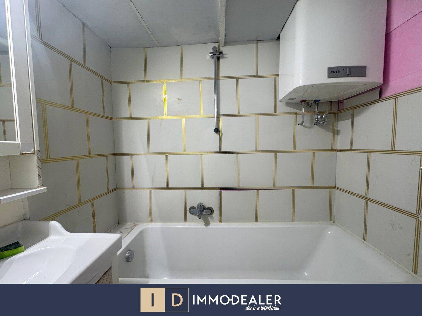 Badezimmer mit Badewanne, Waschbecken und Fliesenwänden, benötigt eine Renovierung.