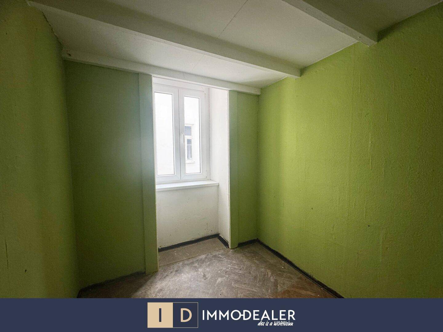 Kleines Zimmer mit grünen Wänden und Fenster, ideal als Kinder- oder Gästezimmer.