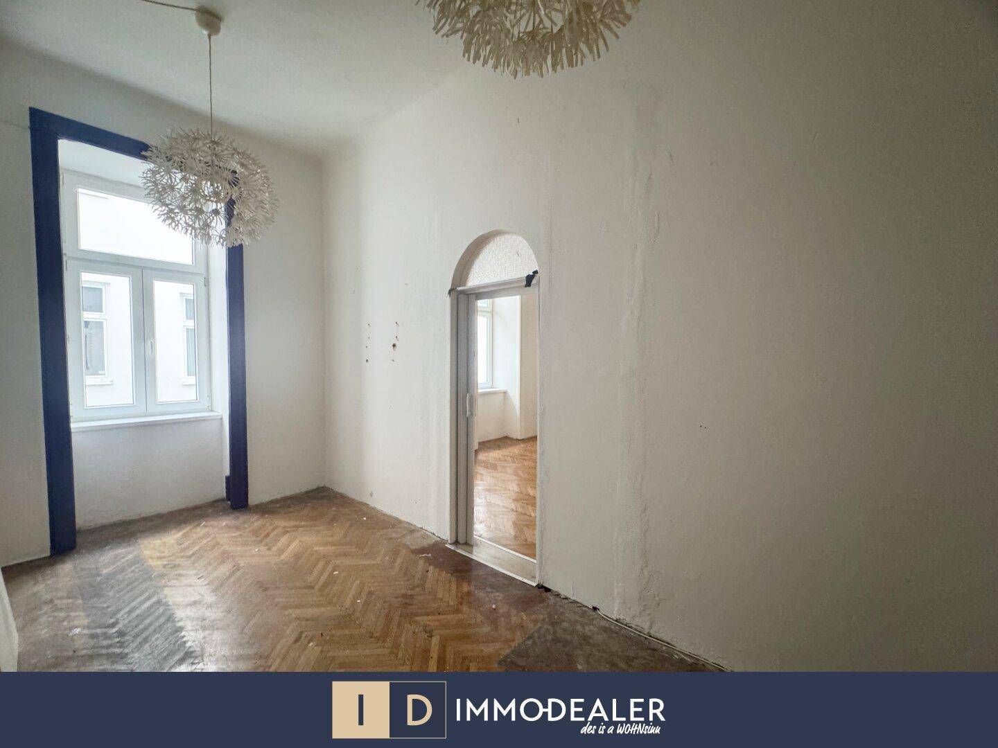 Helles Zimmer mit Parkettboden, dekorativen Leuchten und einem eleganten Torbogen.